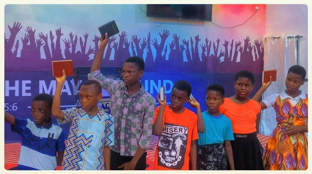 Young people raising the Bibles donated to them by UEWG